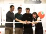 Four people cut a celebratory ribbon together, smiling, at an event backdrop with logos and a Playable Factory sign in the background.