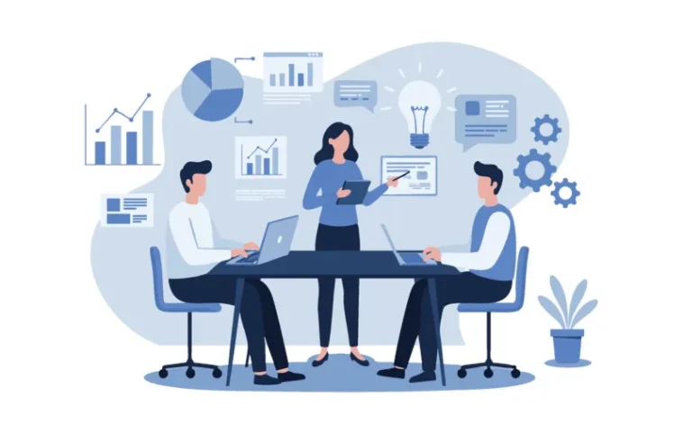 Three colleagues sit around a conference table with laptops while a woman presents a chart.