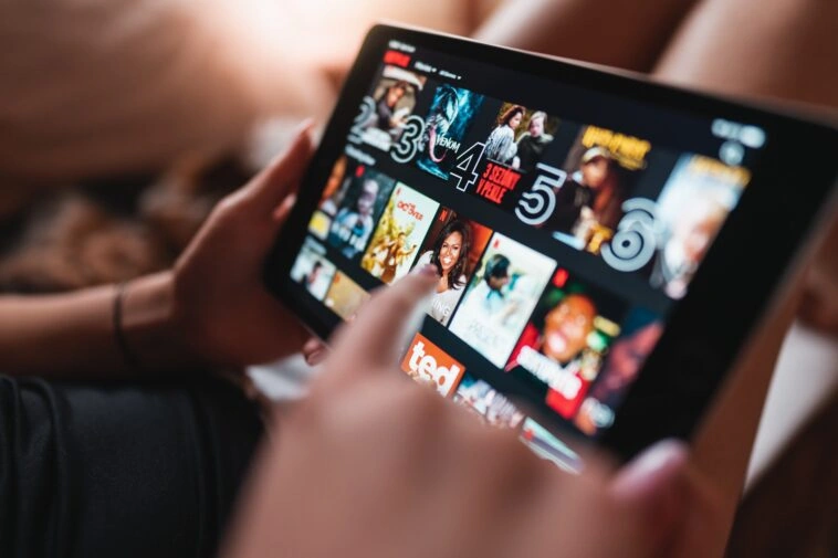 yousafbhutta-tablet-7025855 – mobile marketing reads Close-up of a tablet screen showing a grid of movie posters in a streaming app, with a hand interacting with the display