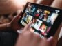 yousafbhutta-tablet-7025855 – mobile marketing reads Close-up of a tablet screen showing a grid of movie posters in a streaming app, with a hand interacting with the display